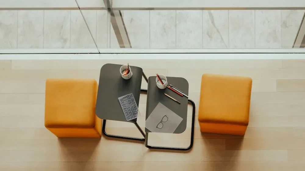 Zwei leere Sitze bzw. Hocker, in orange, von oben abgebildet. Wartend auf das Coaching Gespräch.