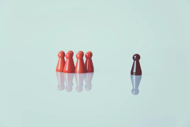 Leadership Development, Spielfiguren - eine Spielfigur steht einzeln als Leader, eine Gruppe von Spielfiguren daneben